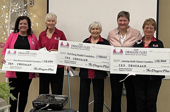 Three women holding giant cheques